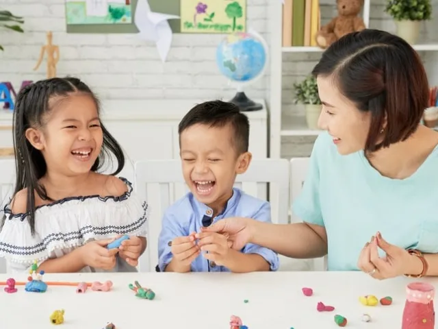 positive parenting mother laughing with kids during crafting by DragonImages istock min 1
